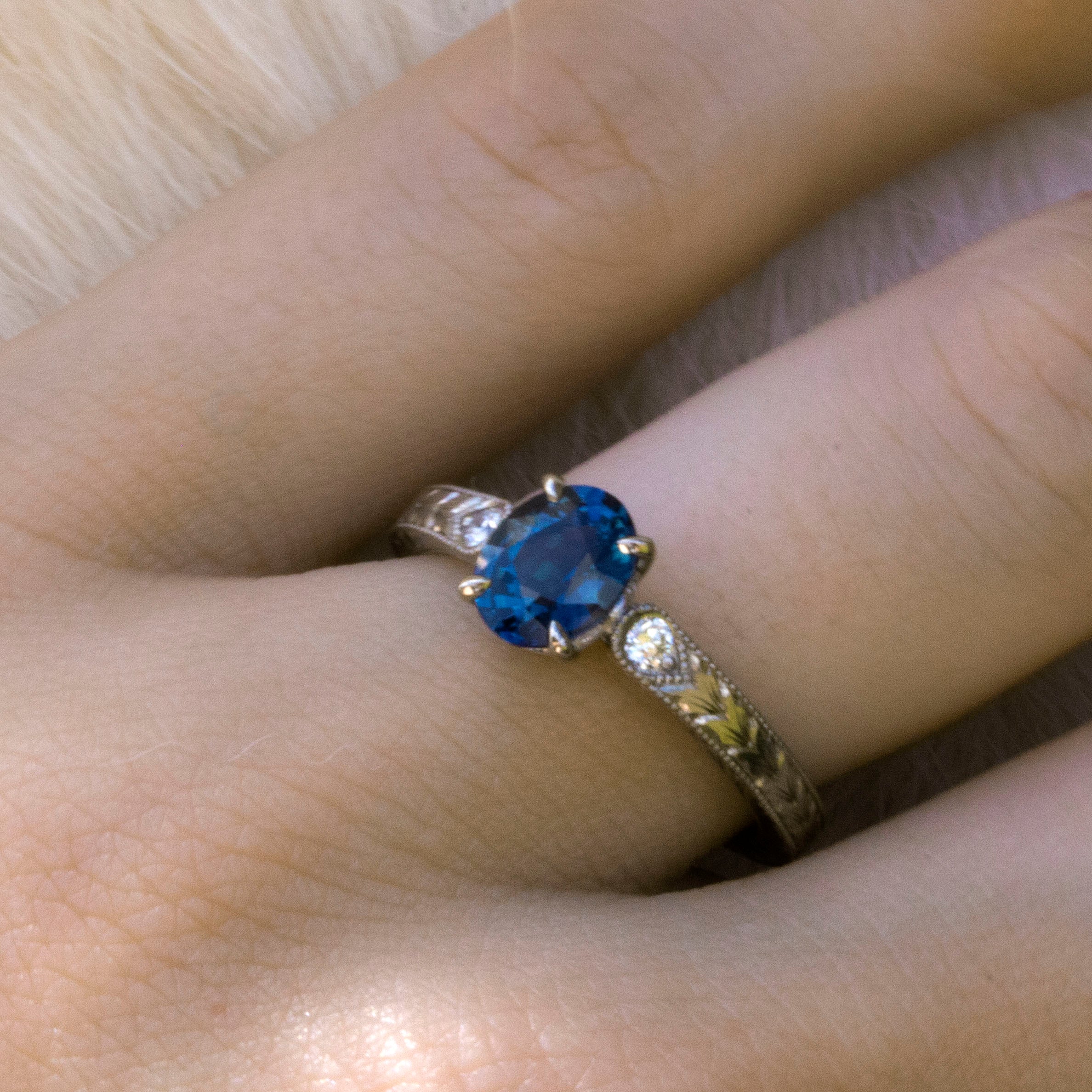 blue sapphire and diamond engraved engagement ring on hand