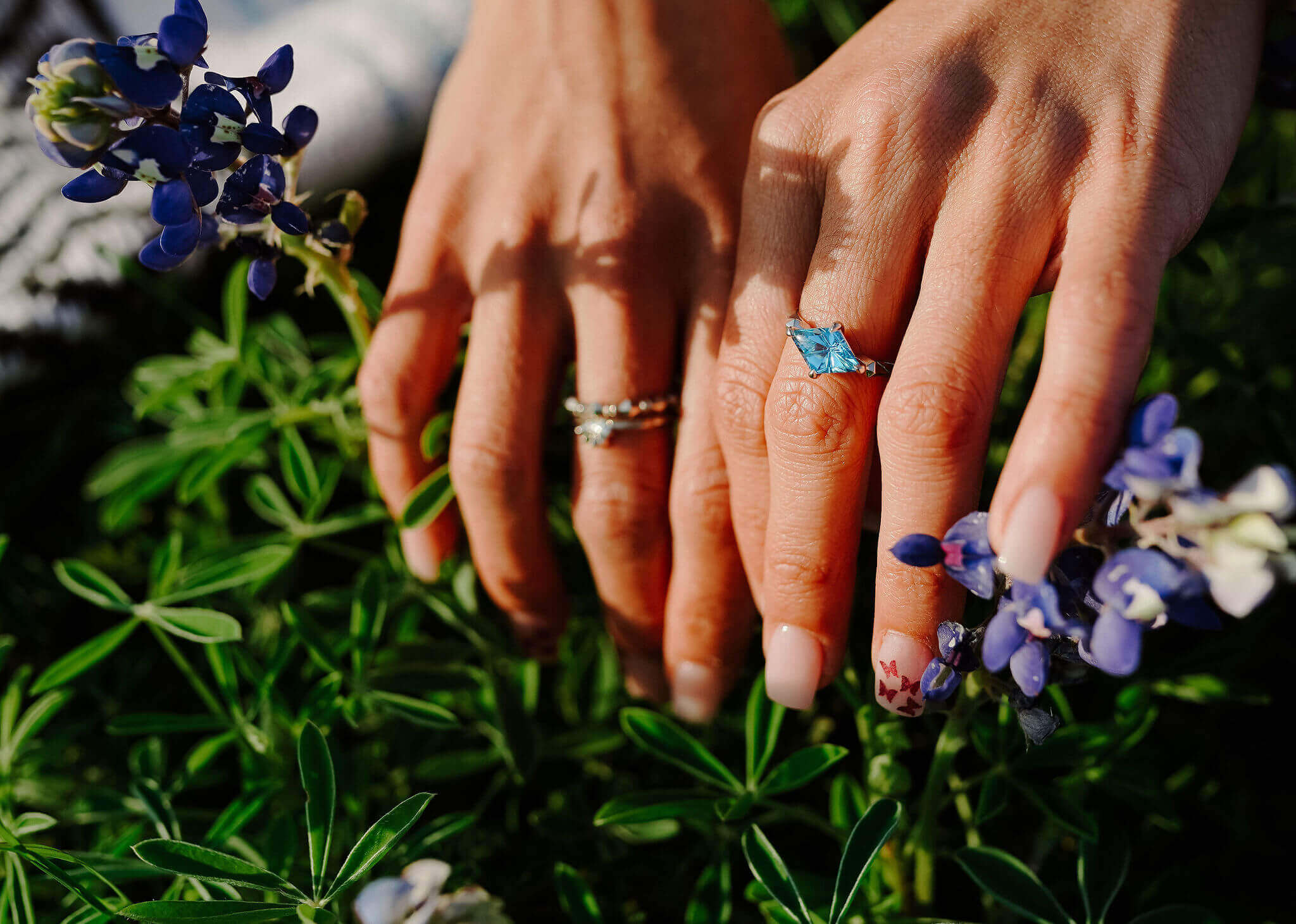 Jewelry on model's hand with bluebonnet flowers
