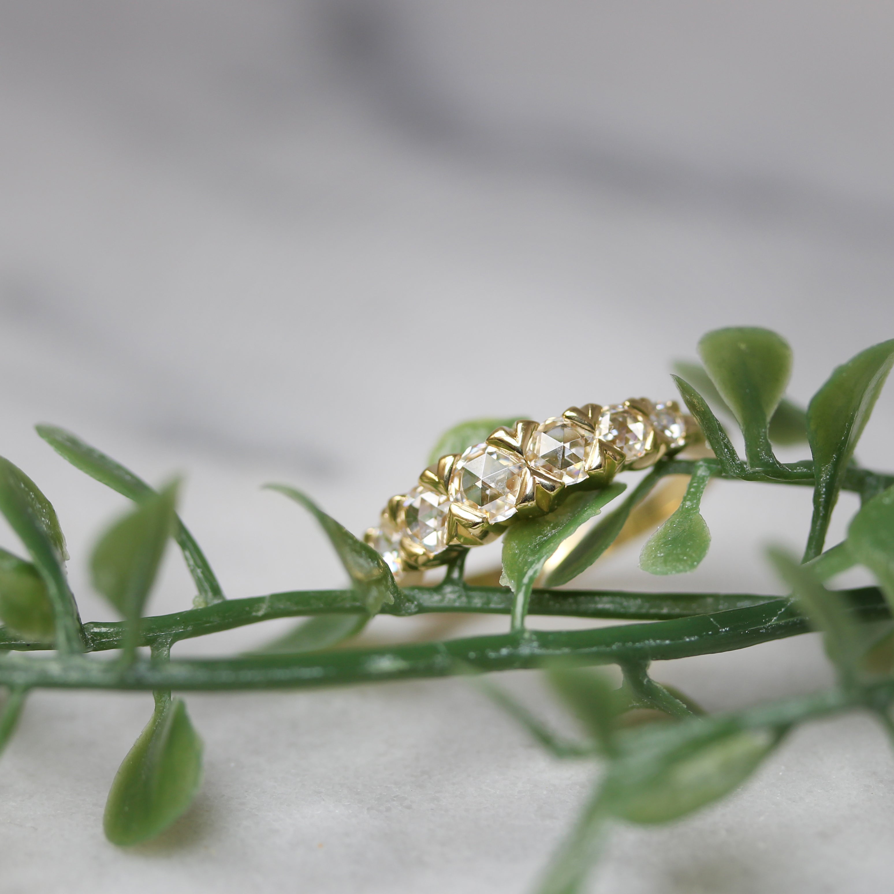 Rose cut moissanite and yellow gold ring on greenery