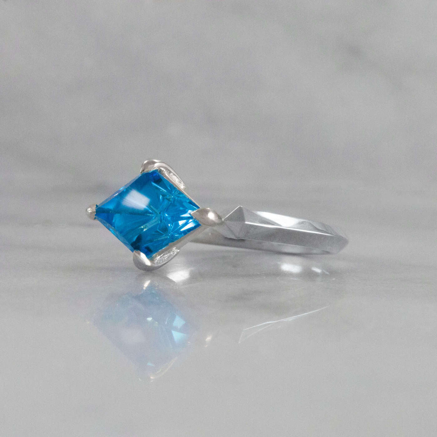 Kite Shaped Blue Topaz Pyramid Ring laying down angled view